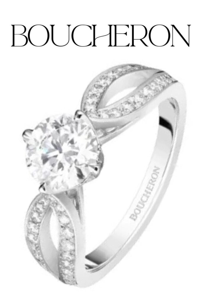 The Boucheron Pont de Paris engagement ring features a stunning round brilliant diamond set in a crown-like, four-prong mounting, exuding elegance with its high clarity and color. The band is crafted from polished white gold, adorned with sparkling pavé diamonds along intertwining strands that form a delicate, modern silhouette. This design embodies the luxury and intricate craftsmanship that Boucheron is renowned for.