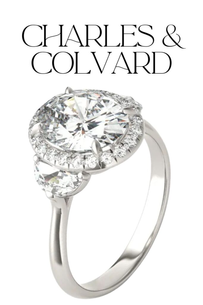 The Charles & Colvard Oval Luna Halo Engagement Ring features a striking oval center stone surrounded by a halo of smaller round diamonds, with unique half-moon stones elegantly placed on each side. Crafted in high-quality platinum, the smooth, polished band complements the dazzling display of clarity and brilliance, making this ring a stunning symbol of love.