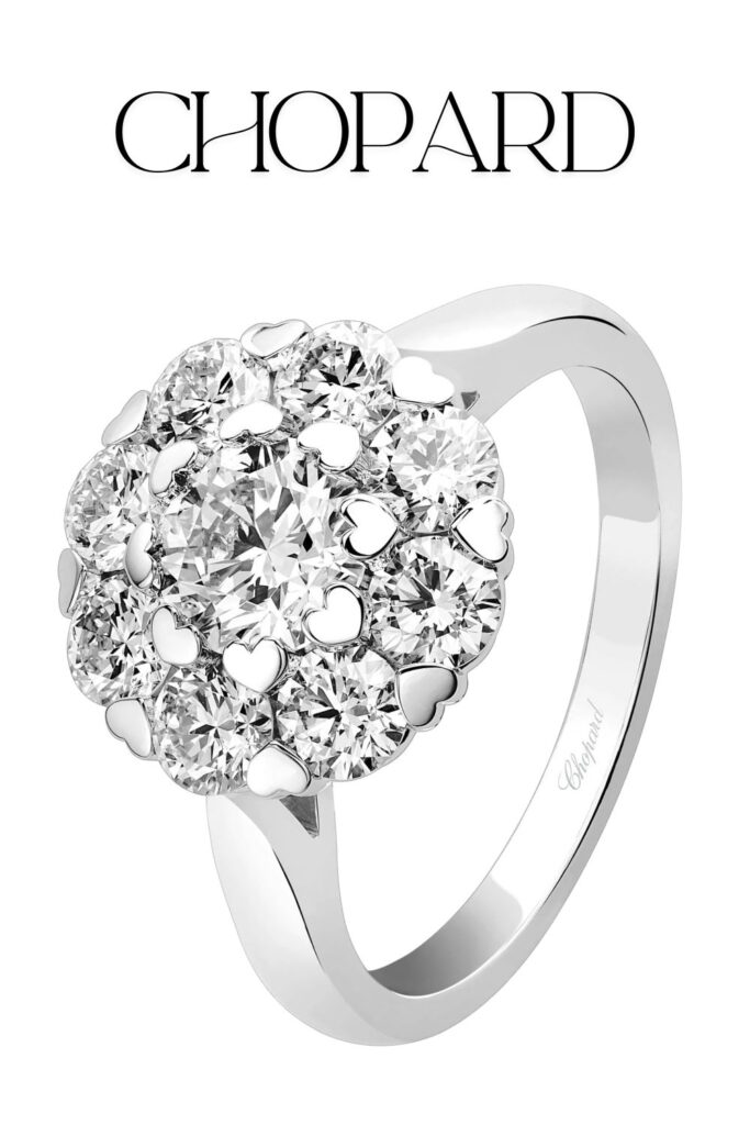 The Chopard L'Heure du Diamant Ring features a stunning floral cluster design with a central round diamond surrounded by smaller diamonds, cut with high clarity and brilliance. This ring is crafted from ethical white gold, enhancing the exquisite sparkle of the diamonds. The delicate band and intricate setting exemplify Chopard's commitment to luxury and craftsmanship.