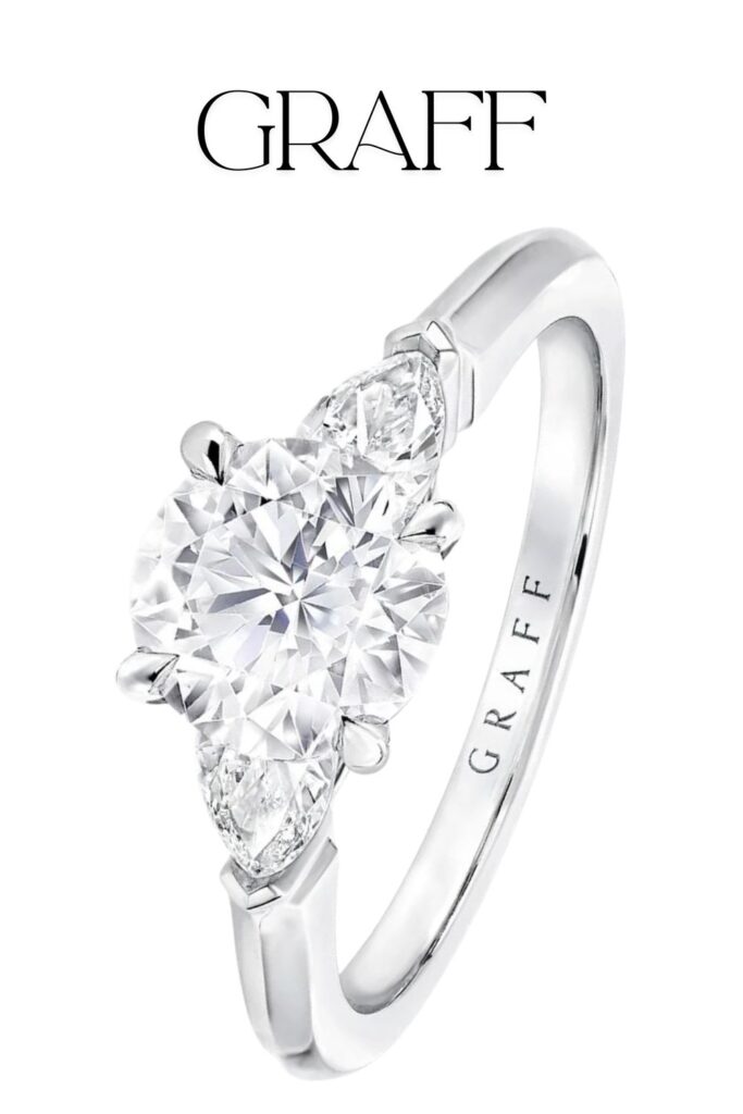 The Graff Promise engagement ring features a brilliant round diamond at its center, complemented by pear-shaped side stones, all set in exquisite platinum. The elegant design showcases a classic solitaire setting, enhancing the clarity and sparkle of the diamonds, which display exceptional craftsmanship. The polished band adds a sophisticated touch, making this ring a timeless symbol of love and commitment.