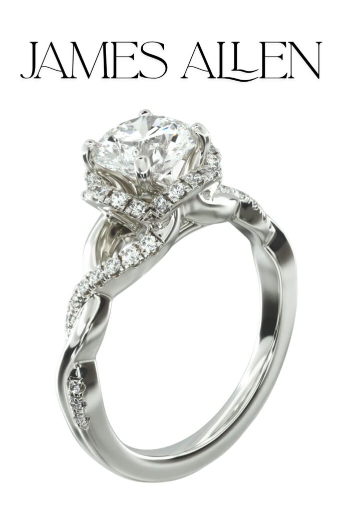 This James Allen engagement ring features a stunning round brilliant-cut diamond set in 14K white gold, accentuated by a delicate pavé halo and interlaced band design that adds elegance. The ring showcases exceptional clarity and brilliance, with smaller diamonds embedded along the twisted band for added sparkle. Its vintage-style aesthetics and intricate settings emphasize the craftsmanship while enhancing the overall allure.