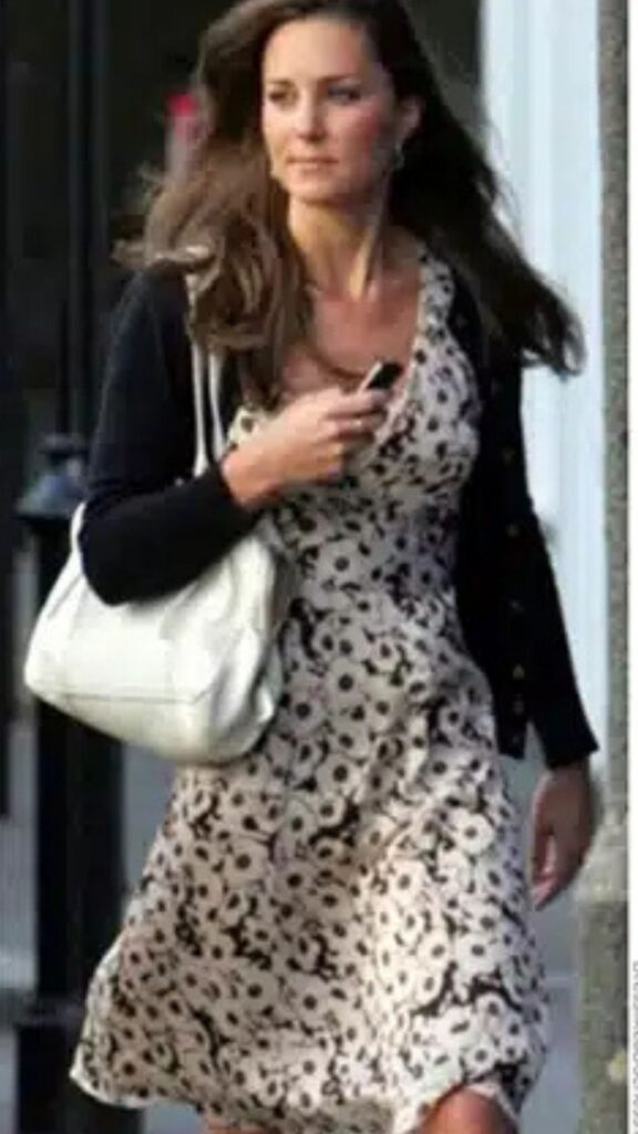 The Prada White Boston Bag complements the floral print dress and black cardigan by adding a touch of elegance and sophistication. Its structured design contrasts with the soft silhouette of the dress, while the neutral white color harmonizes with the overall palette, enhancing the outfit's fresh and chic appeal. The handbag's practicality and style reflect an effortless blend of fashion and function, typical of Kate Middleton's polished aesthetic.