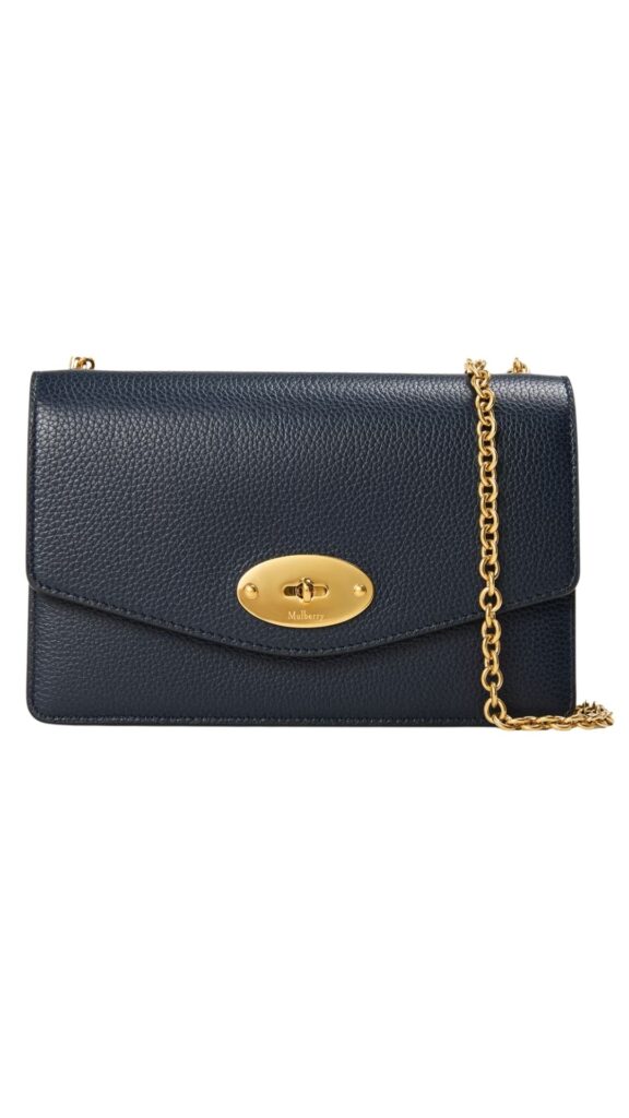 The Mulberry Small Darley Purse in Night Sky features a sleek, rectangular silhouette crafted from luxurious textured leather. It showcases a rich navy color with a distinctive gold-tone twist lock closure and an adjustable chain strap for versatility. This handbag combines elegance and functionality, making it perfect for both casual and formal occasions.